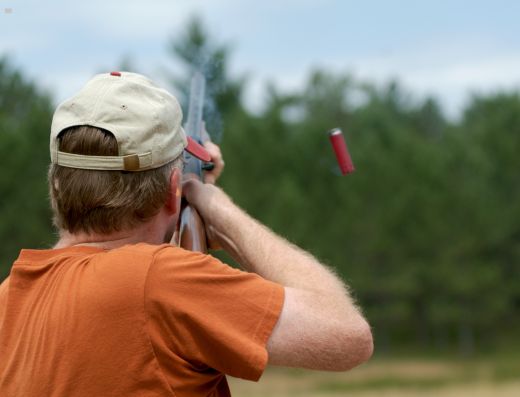 Shooter aiming at a clay target during a competitive trap shooting event.
