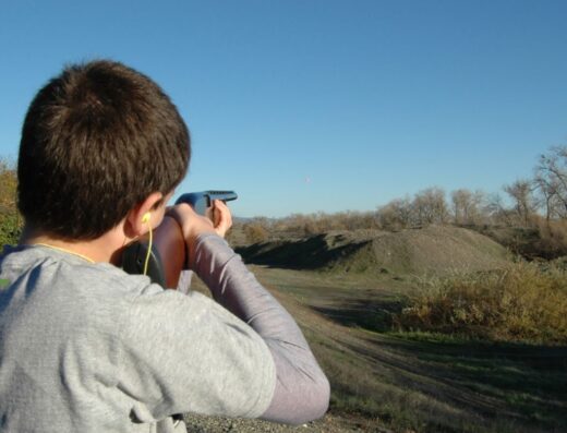 Shooter aiming at clay target under blue sky