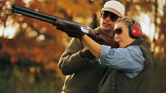 Instructor guiding a group of new clay shooters at an outdoor range
